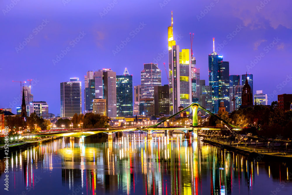Panoramic view cityscape skyline of business district with skyscrapers and mirror reflections in the river Main during sunset blue hour, Frankfurt am Main. Hessen, Germany