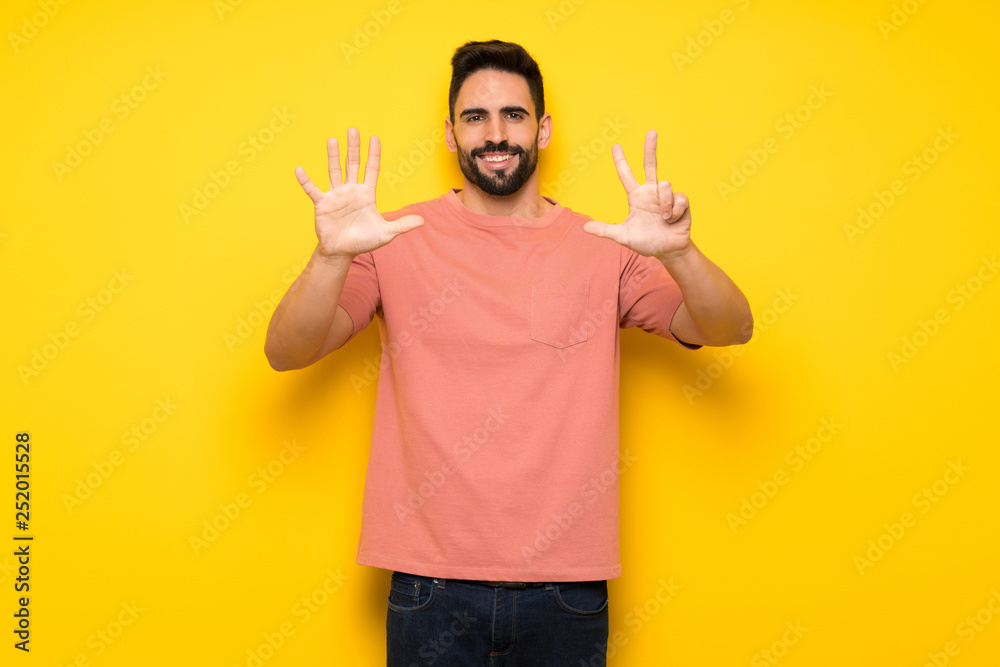 Handsome man over yellow wall counting eight with fingers Handsome man over yellow wall counting eight with fingers