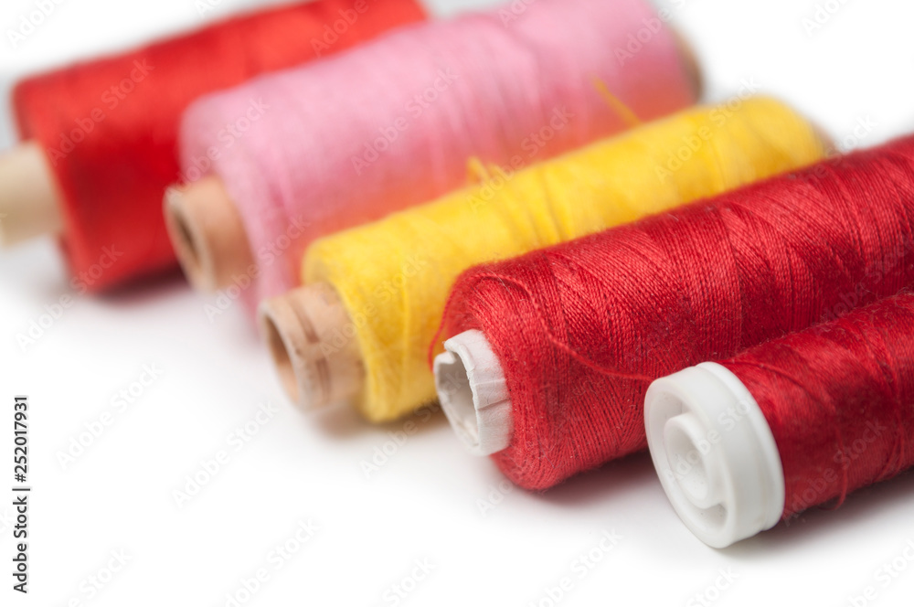 closeup of sewing thread spool bobbins on white background closeup of sewing thread spool bobbins on white background