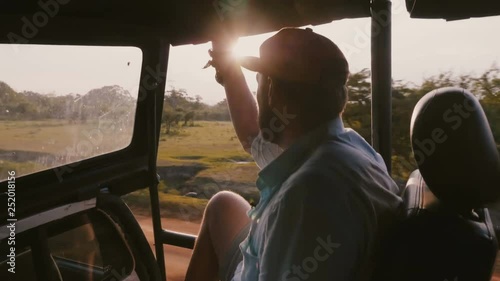 Wallpaper Mural Young happy relaxing traveler man on epic sunset tropical forest excursion ride in safari car, sunlight shines through. Torontodigital.ca