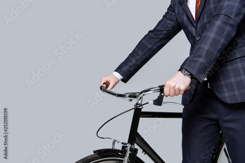 cropped view of businessman with bike isolated on grey