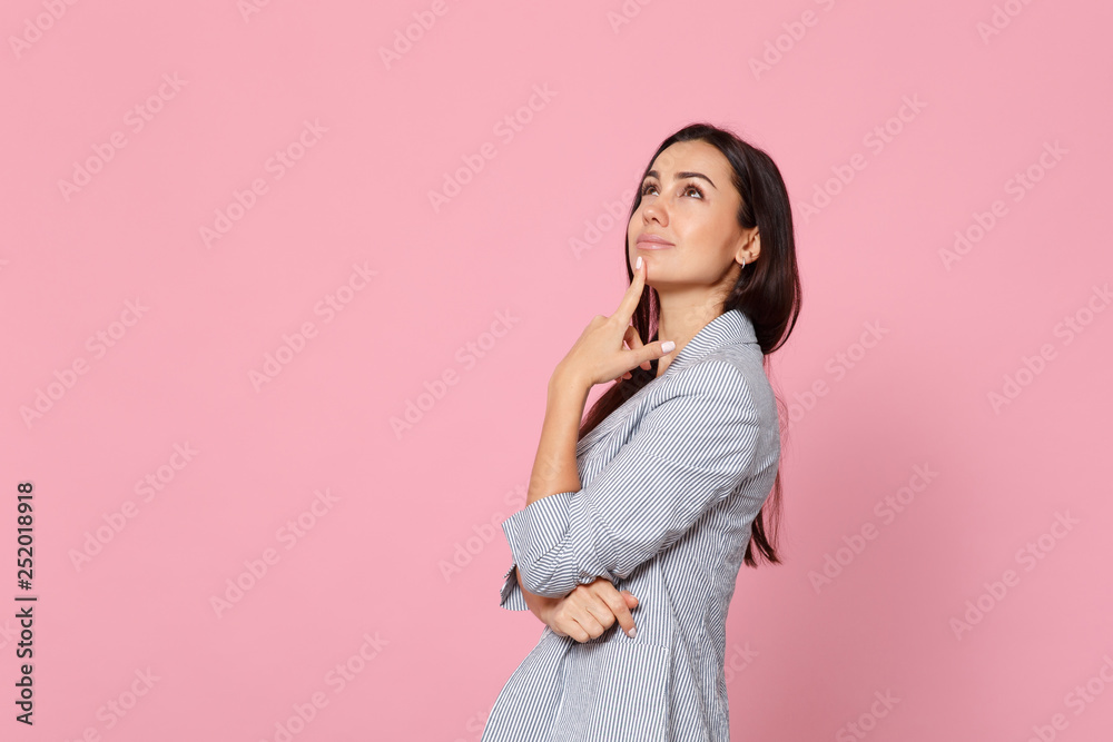Side view of pensive dreamful young woman in striped jacket looking up put hand prop up on chin isolated on pink pastel wall background. People sincere emotions, lifestyle concept. Mock up copy space. Side view of pensive dreamful young woman in striped jacket looking up put hand prop up on chin isolated on pink pastel wall background. People sincere emotions, lifestyle concept. Mock up copy space.
