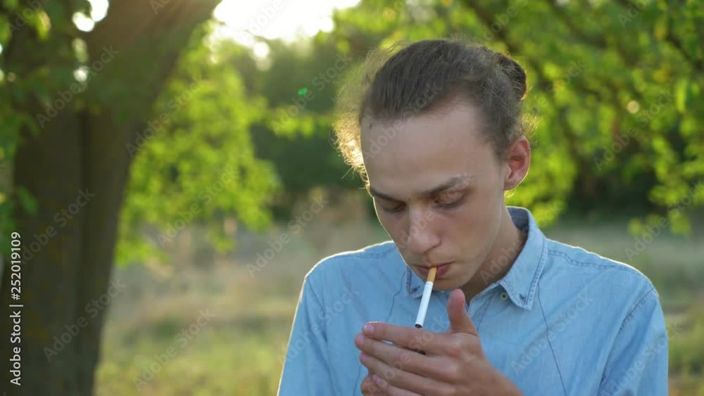 young cute man with tied hair smoking cigarette outdoors, sunset, 4k young cute man with tied hair smoking cigarette outdoors, sunset, 4k
