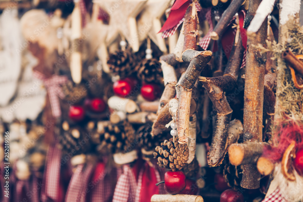 Blurred Christmas background with natural colourful decorations - wooden stars, pine cones, apples, red clothes. Place for copy on left. Close-up view.