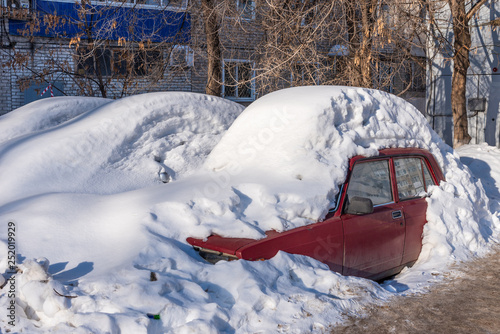 Car covered with snow in the spring