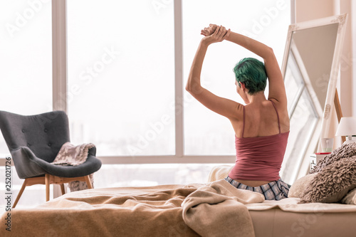 Green-haired woman in pajamas waking up in the morning photo