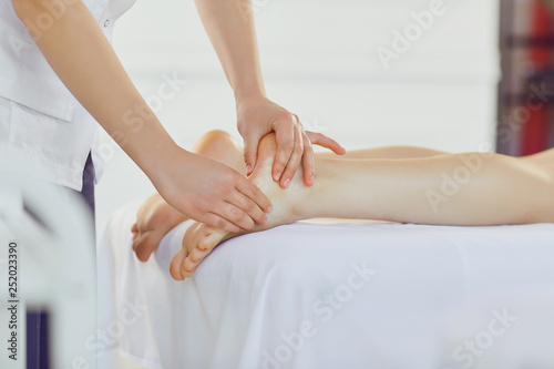 Therapist massaging feet of client lying
