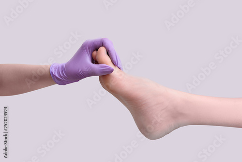 Hand in glove holds female leg after pedicure. Isolate