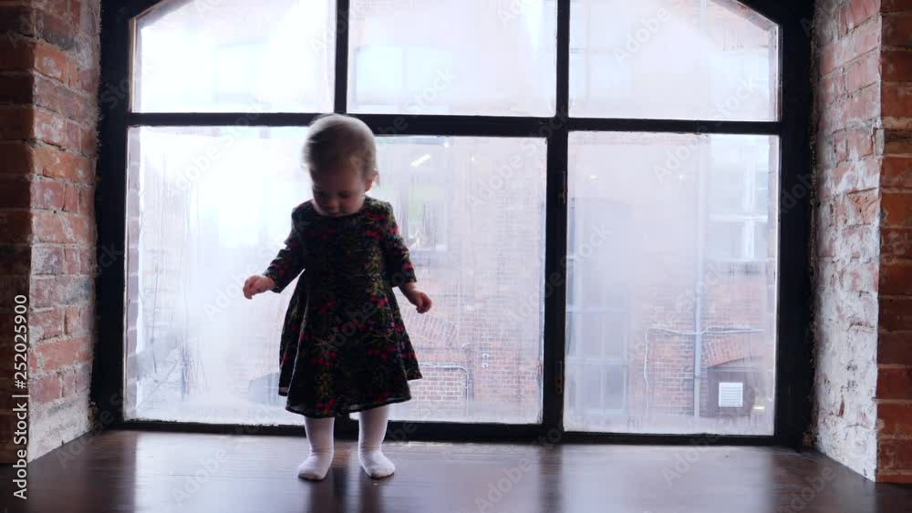 Little baby child girl walk on a windowsill with misted window glass Little baby child girl walk on a windowsill with misted window glass