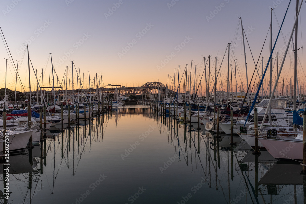 A sunset shot of a marina with the Auckland Harbour bridge on the background