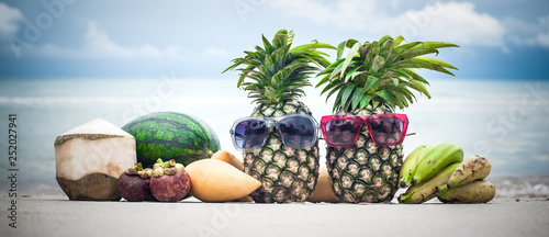 Fototapeta Tropical fruit mix on the beach. Stylish pineapple with sunglasses