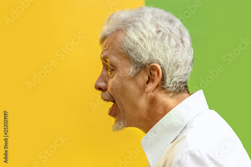 Screaming, hate, rage. Crying emotional angry man screaming on studio background. Emotional senior face. male half-length portrait. Human emotions, facial expression concept. Trendy colors