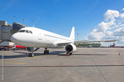 Passenger airplane is parked connected by a ladder at the terminal building in the airport © aapsky