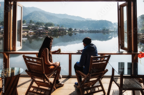 Young loving couple are looking at each other tenderly and drining coffee in morning.