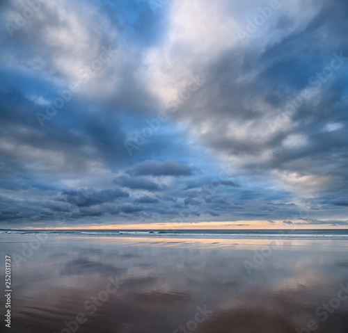 Clouds at sunset reflected in wet sand of wide Inverboyndie Beach with Atlantic Ocean surf at Boyndie Bay Aberdeenshire Scotland UK
