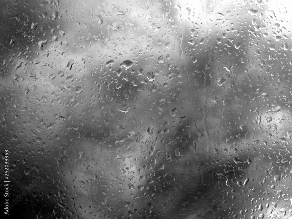 Abstract black and white image of storm clouds and a window pane full of rain drops Abstract black and white image of storm clouds and a window pane full of rain drops