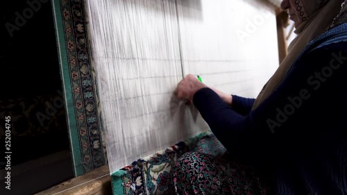 Traditional woman weaving Turkish carpet. Making Persian carpet by hand in classic style. Creating handmade patterned rug using proper technique.