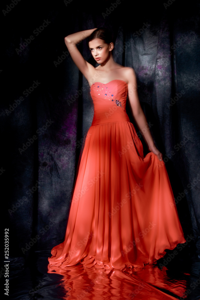 Beautiful woman in red evening dress on dark background