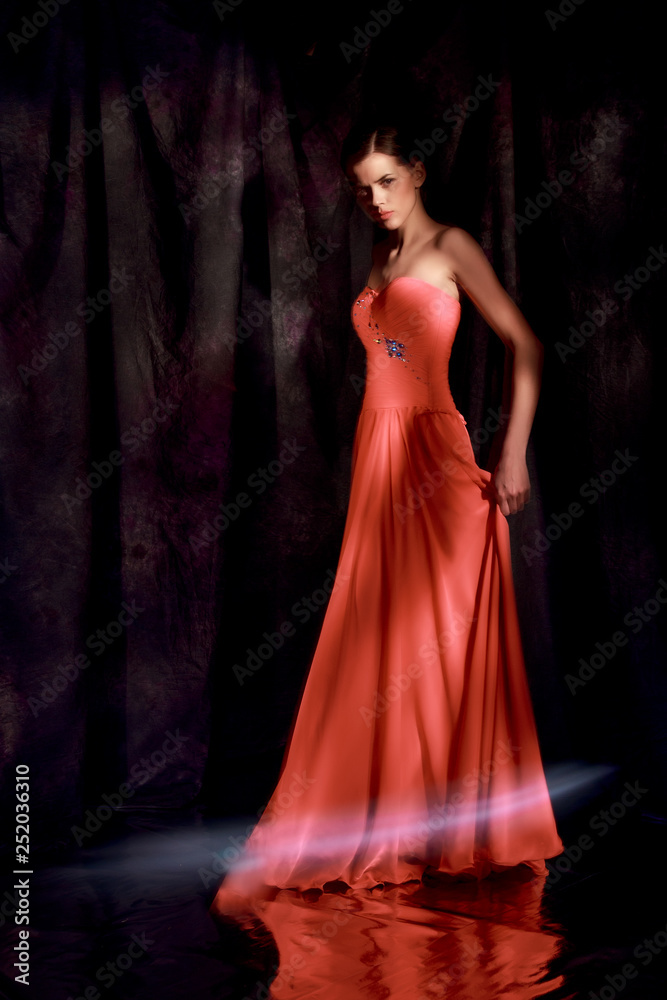 Beautiful woman in red evening dress on dark background