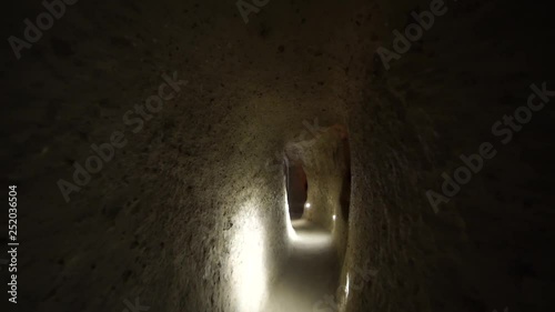Dark Derinkuyu underground city caves in Cappadocia. Walking through ancient carved rock dwellings deep in the ground in Turkey. Long claustrophobic narrow passages.