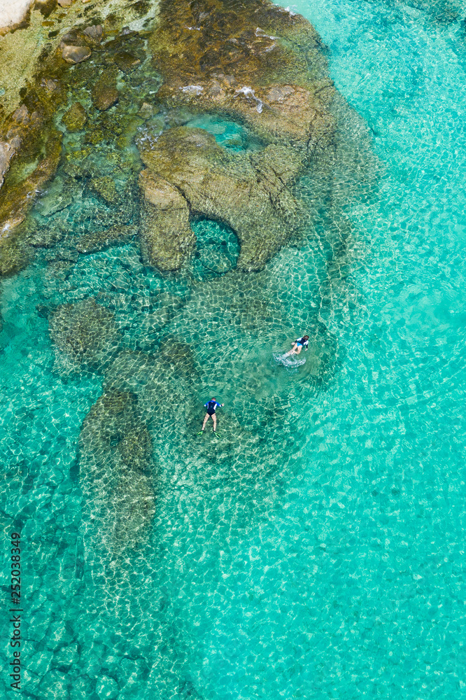 Fototapeta premium View from above, stunning aerial view of some tourists who do snorkeling in a beautiful, transparent and turquoise sea, Phi Phi Island, Thailand.