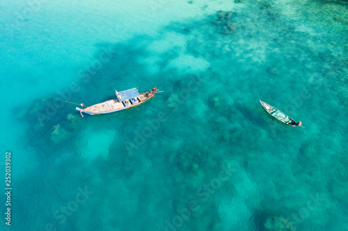View from above, stunning aerial view of two traditional long-tail boats floating on a turquoise and clear sea. Tropical beach with white sand, Freedom beach, Phuket, Thailand.