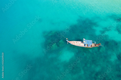 View from above, stunning aerial view of a traditional long-tail boat floating on a turquoise and clear sea. Tropical beach with white sand, Freedom beach, Phuket, Thailand. © Travel Wild