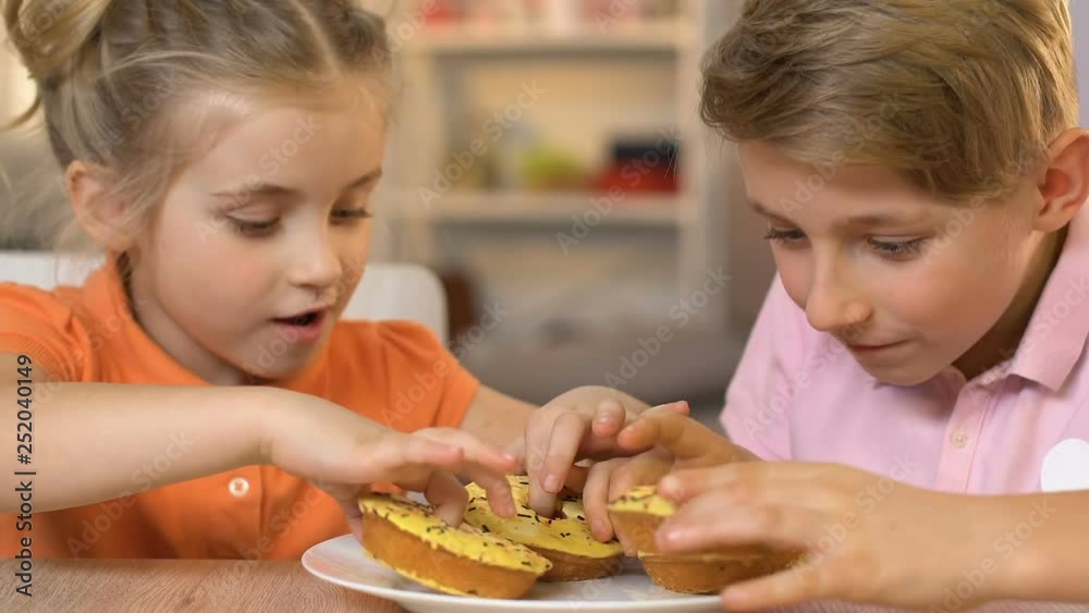 Happy children eating doughnuts with great desire, unhealthy nutrition habits Happy children eating doughnuts with great desire, unhealthy nutrition habits