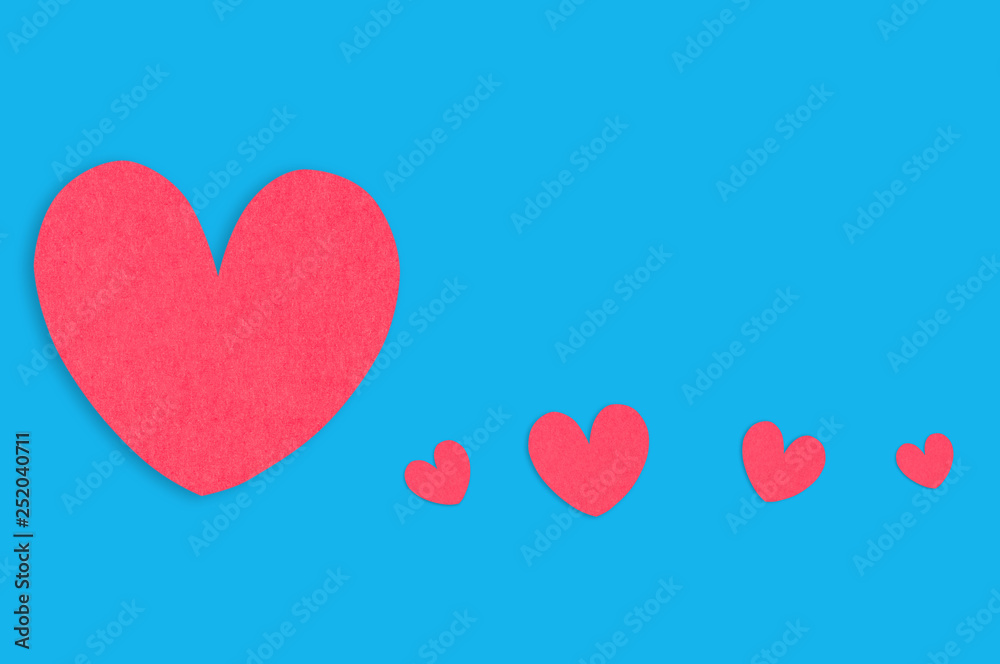 One big red paper heart and row of small hearts on blue table. Top view. Valentines Day concept