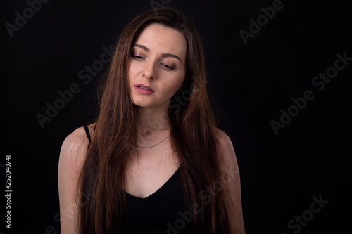 Sad brunette women on a dark background. Depression, negative emotions.