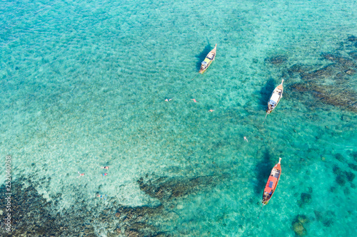 View from above, stunning aerial view of some long-tails boats and tourists who do snorkeling in a beautiful, transparent and turquoise sea, Phi Phi Island, Thailand.