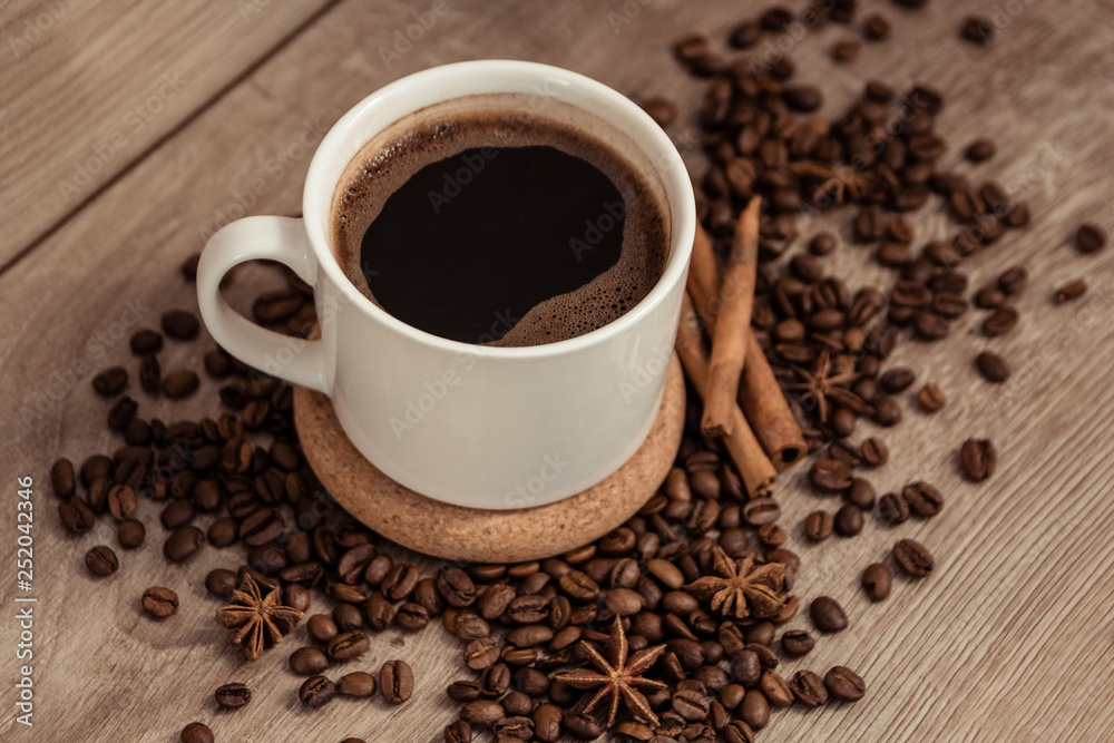 Cup of coffee with beans and spicery on old wooden table Cup of coffee with beans and spicery on old wooden table
