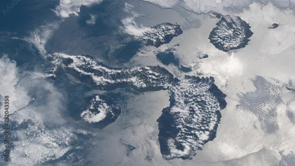 Flying aerial satellite view of turbulent clouds on galapagos island and ocean sea animation. Contains public domain image by Nasa