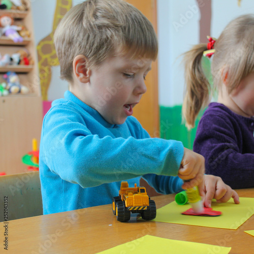 little boy doing crafts. The child glues the paper with glue.