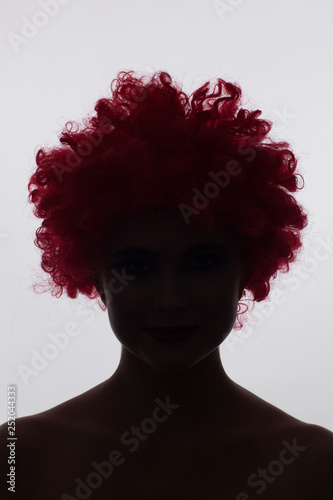 Silhouette of a woman in a red curly wig