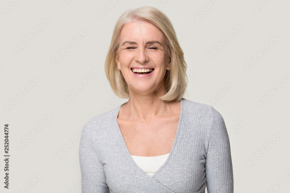 Happy mid aged woman laughing isolated on grey studio background Happy mid aged woman laughing isolated on grey studio background