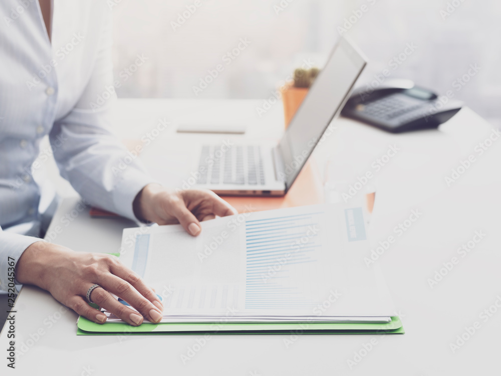 Businesswoman checking financial reports and statements Businesswoman checking financial reports and statements
