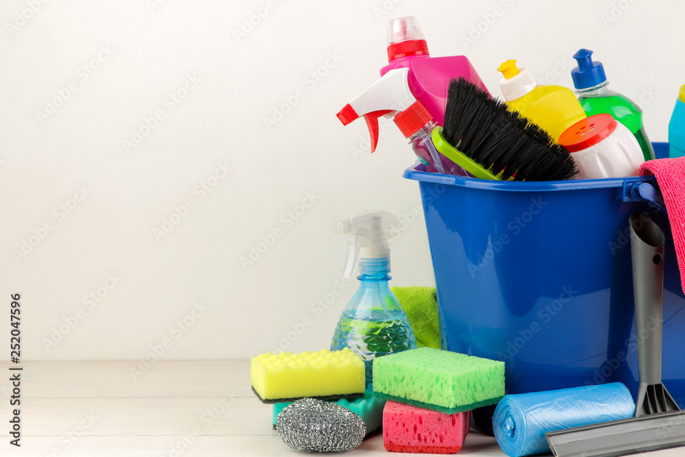 Bottles with detergent and cleaning tools in a bucket on a light background. cleaning. cleaning products. place for text. free place.
