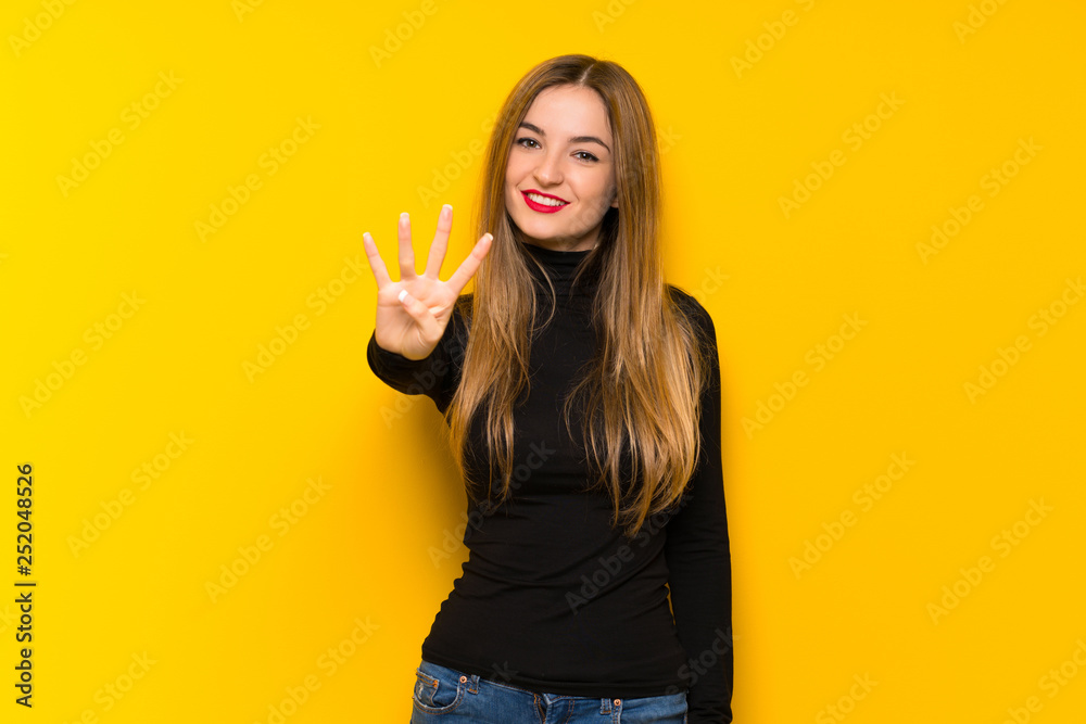 Young pretty woman over yellow background happy and counting four with fingers Young pretty woman over yellow background happy and counting four with fingers