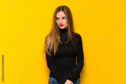 Young pretty woman over yellow background feeling upset