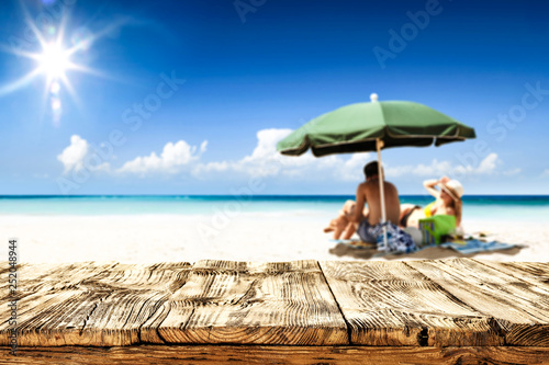 Desk of free space for your product. Beach landscape with people on towel. Ocean water and sun light