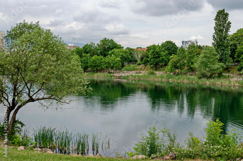 Spring panorama of a part of residential district neighborhood along a lake with green trees  shrubs and flowers  Drujba  Sofia  Bulgaria 