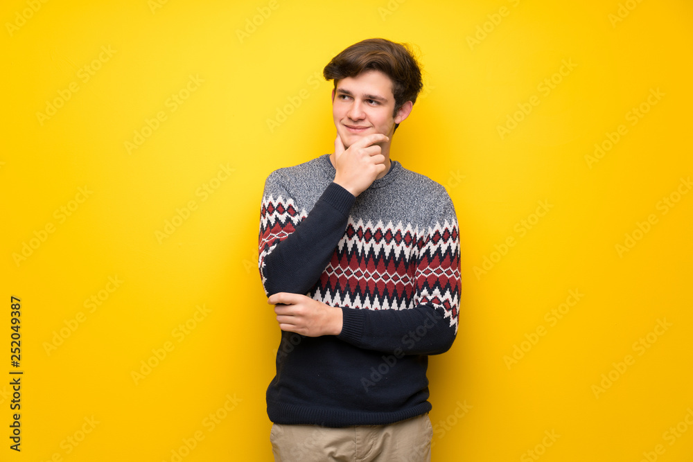 Teenager man over yellow wall looking to the side Teenager man over yellow wall looking to the side