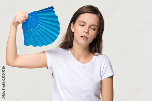 Tired young woman feel overheated suffering from heat waving fan photo