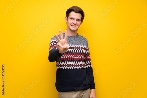 Teenager man over yellow wall happy and counting three with fingers