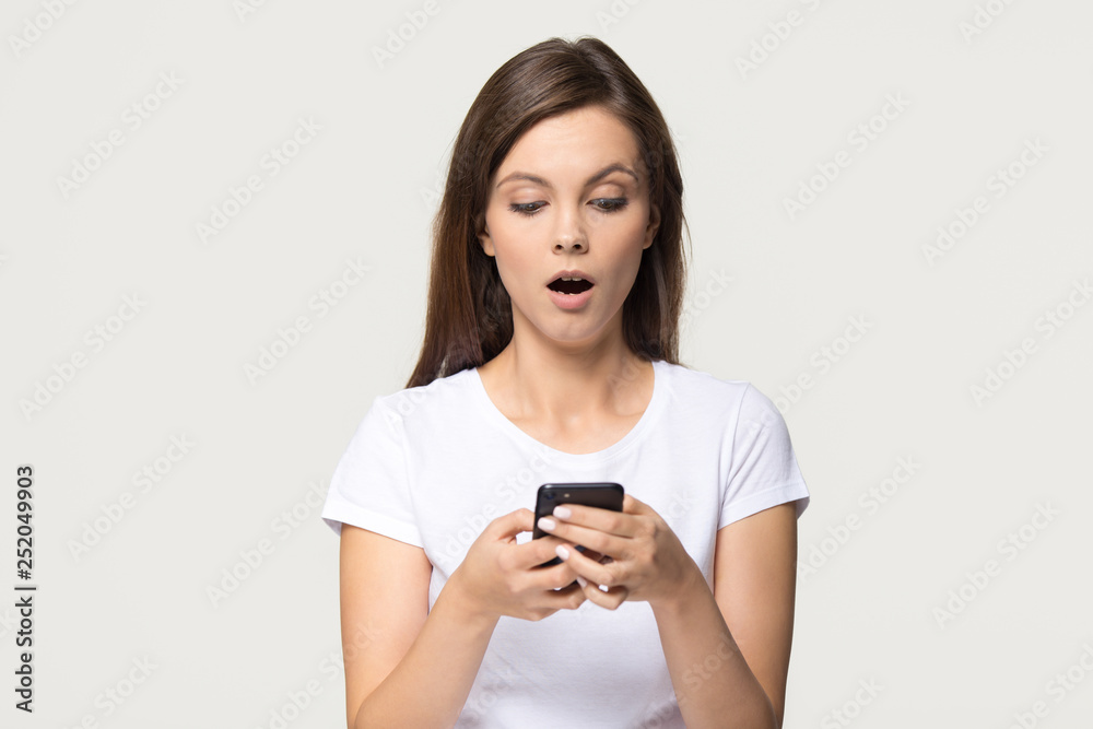 Shocked girl holding phone feeling stunned about unexpected mobile message Shocked girl holding phone feeling stunned about unexpected mobile message