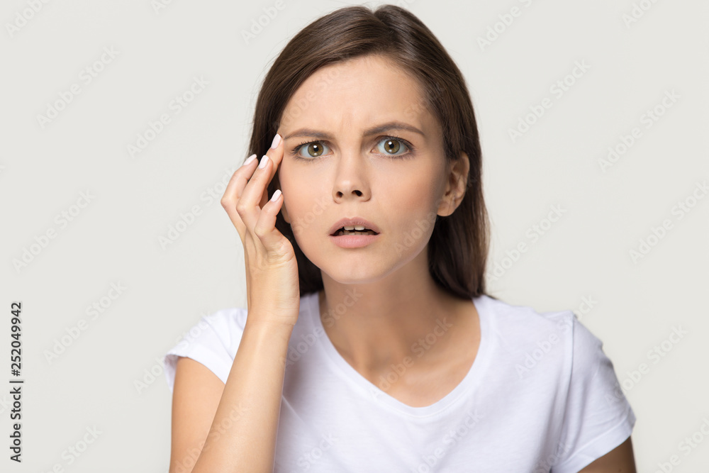 Worried stressed girl checking wrinkles on face looking at camera Worried stressed girl checking wrinkles on face looking at camera