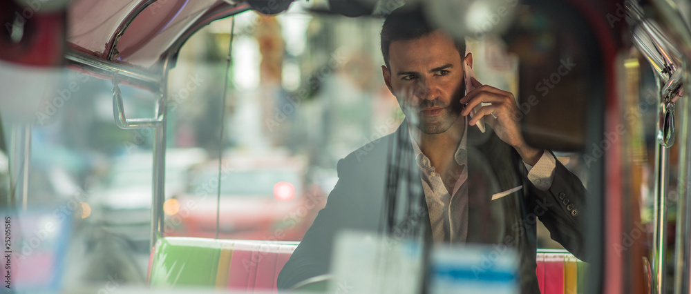 Caucasian Business Man Talking in a cell phone in Tuk Tuk, Chinatown Bangkok Thailand