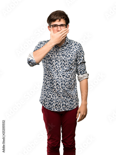 Teenager man with flower shirt and glasses covering mouth with hands for saying something inappropriate over isolated white background