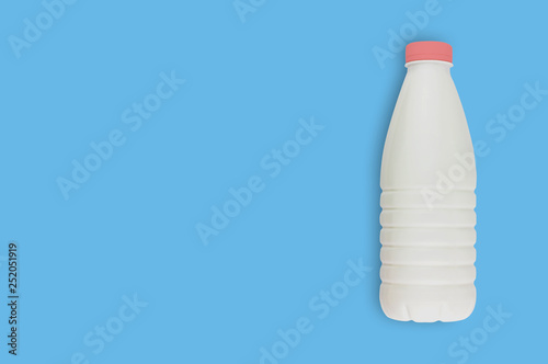 Fresh dairy product in full plastic bottle for milk, kefir or yoghurt with red cap on blue table on kitchen. Copy space for your text. Top view. Cooking concept